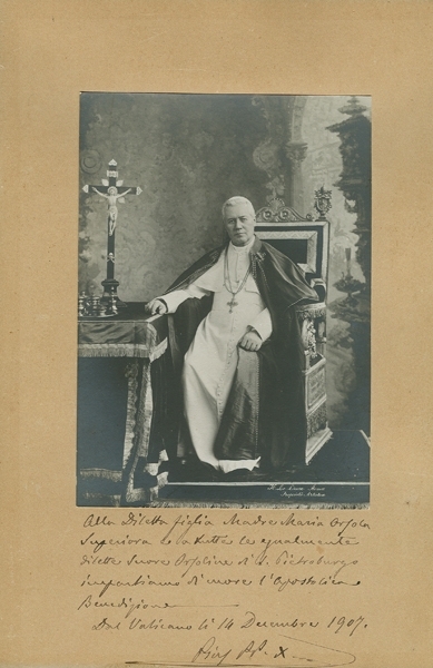 Fotografia przedstawia papieża św. Piusa X siedzącego na okazałym krześle. Pod zdjęciem odręczne notatki. 